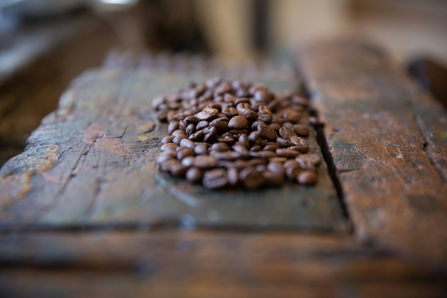 Mörkt rostade kaffebönor som vilar på en rustik träyta.