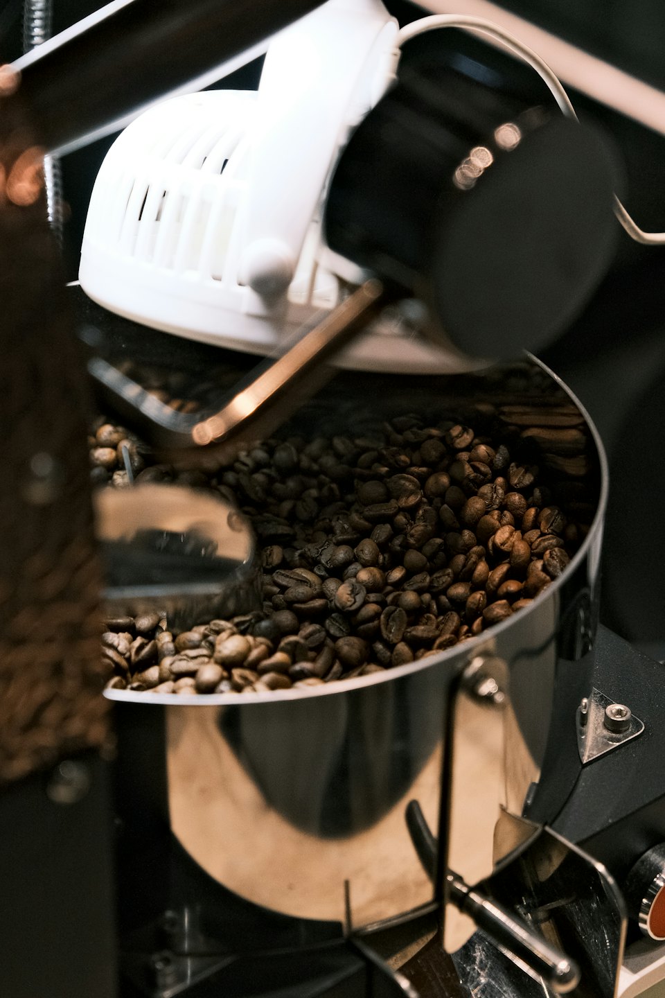 Rostade kaffebönor tumlar i en trumma av rostfritt stål.