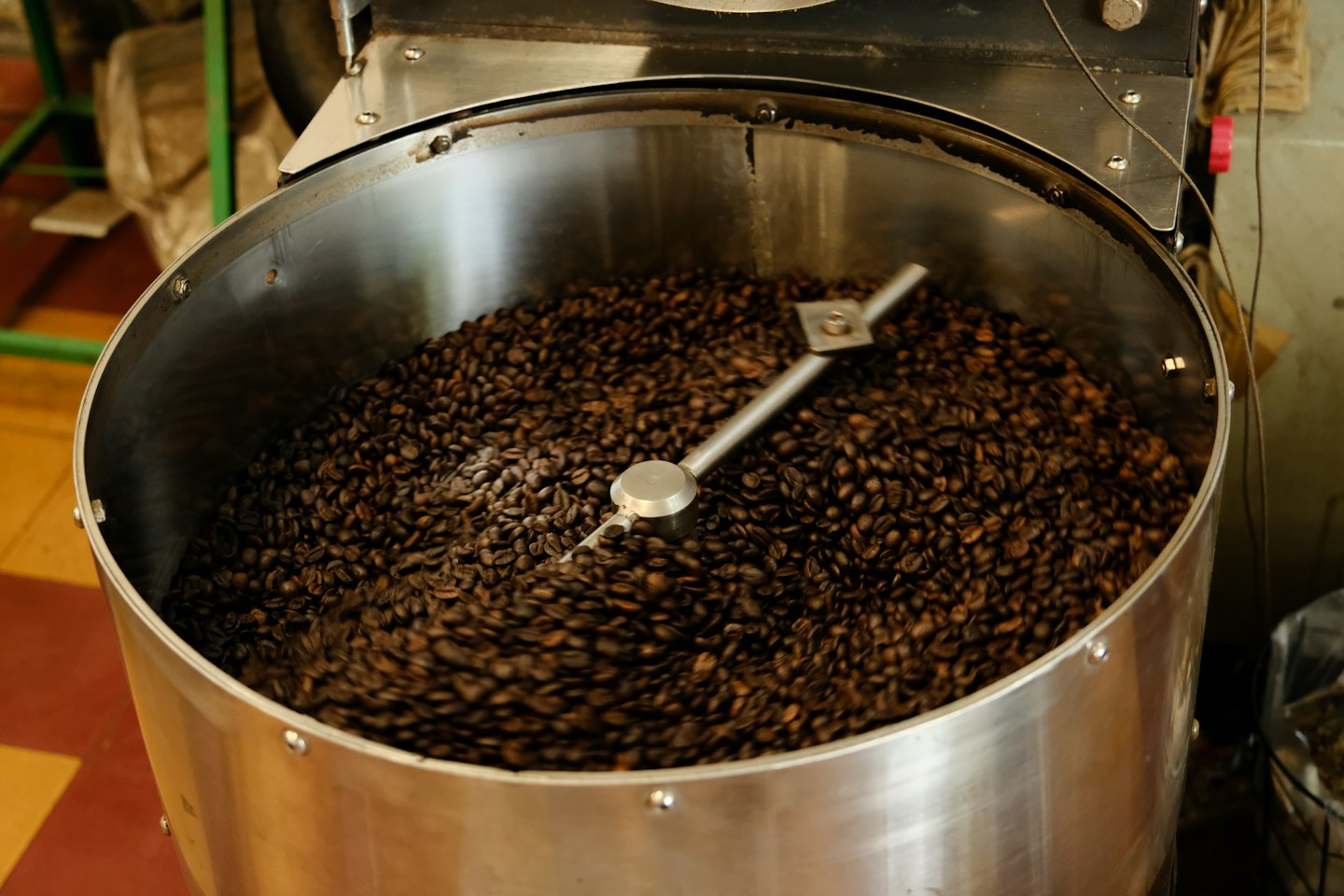 Mörkt rostade kaffebönor roterar i en industriell metallrost.