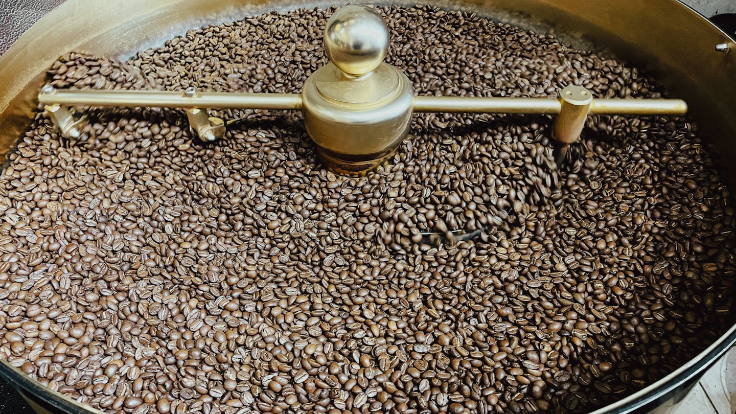 Metallarm rör om kaffebönor i en industriell rost.