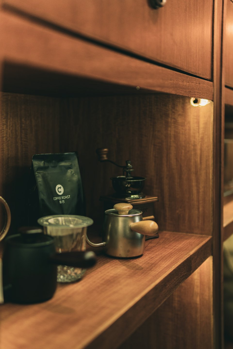 Kaffebryggningsutrustning och kaffebönor arrangerade på en trähylla.